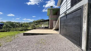 Vista externa da casa com garagem e área de concreto no quintal.