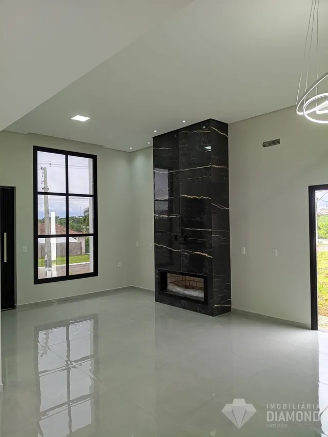 Ambiente interno de uma sala ampla com piso claro e parede de pedra escura.