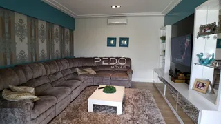 Sala de estar com sofá grande e painel decorativo na parede.