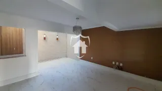 Sala ampla com piso claro e parede marrom na residência.