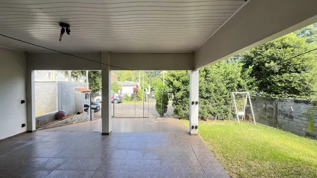 Área externa pavimentada com piso de cerâmica e gramado.