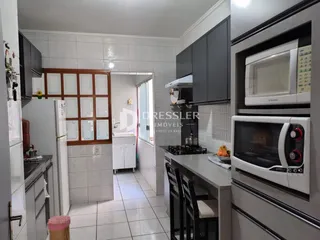 Vista interna de uma cozinha com armários e piso de cerâmica.