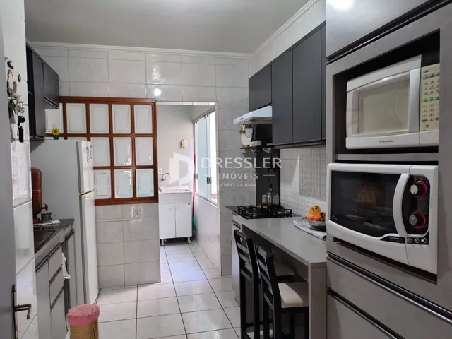 Vista interna de uma cozinha com armários e piso de cerâmica.