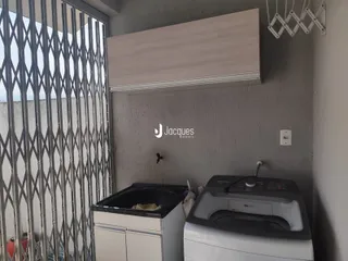 Interior de uma área de serviço com máquina de lavar e pia em um imóvel no Brasil.