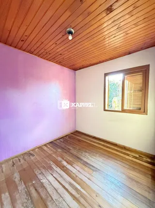 Interior de um cômodo com piso de madeira e teto de tábuas de madeira.