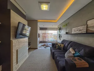 Sala de estar com sofá e televisão em um apartamento no Brasil.