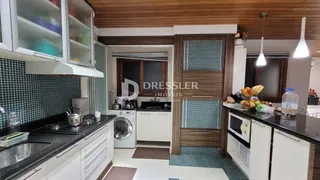 Vista da cozinha com armários brancos e detalhes em madeira.