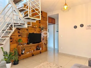 Interior de uma sala com escadaria de madeira e painéis rústicos.