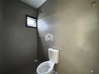 Parede de um banheiro com janela e vaso sanitário.