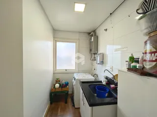 Vista interna de uma cozinha com piso de madeira e janela.