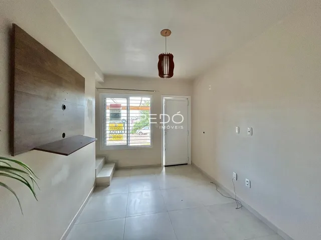Hall da casa com piso de cerâmica e paredes brancas.
