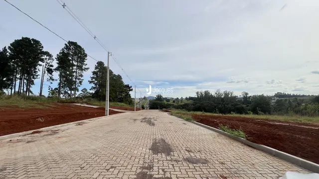 Uma estrada pavimentada com blocos de concreto se estende por uma área de terra.