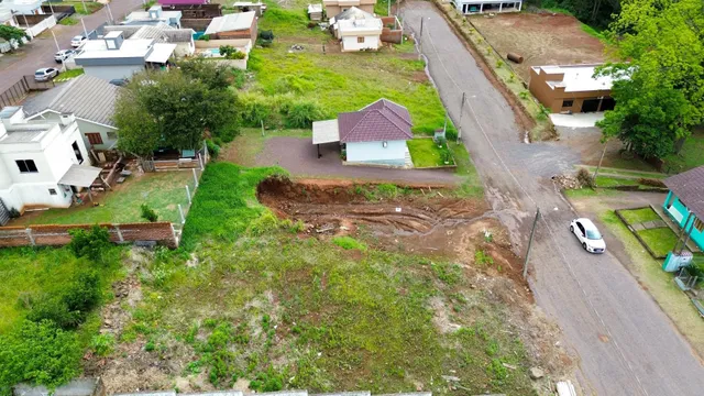 Vista externa de um terreno com vegetação e uma residência em construção.