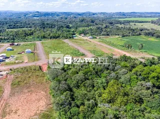 Vista aérea de um terreno rural com campos abertos e vegetação densa.