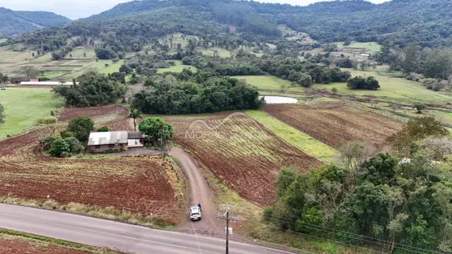 Vista panorâmica de uma paisagem rural com campos cultivados e colinas ao fundo.