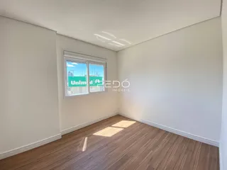 Interior de um cômodo com paredes brancas e piso de madeira.