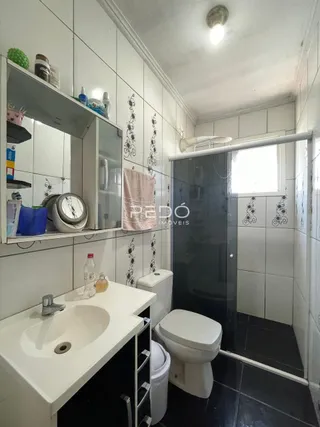 Foto de um banheiro com revestimento cerâmico branco e louças sanitárias.