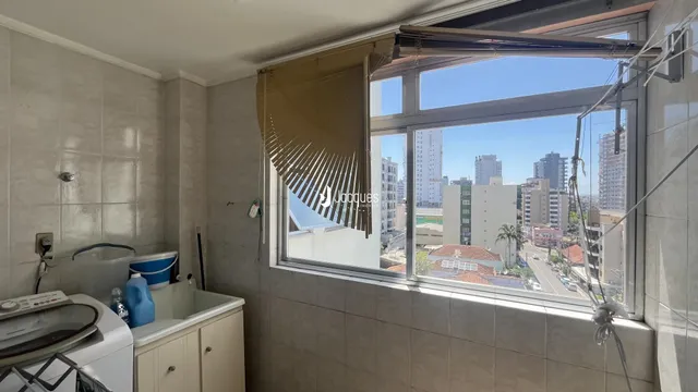 Interior de um cômodo com azulejos e janela de vista para a cidade.