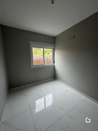 Uma sala com piso de porcelanato claro e janela de tijolos aparentes.