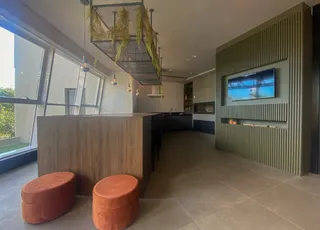 Ambiente interno moderno com bancada de madeira e televisão na parede.