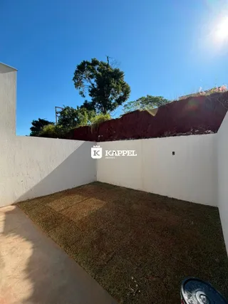 Vista de um jardim com grama e uma parede branca no fundo.
