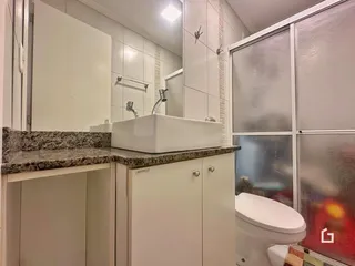 Foto interna de um banheiro com bancada e box de vidro.