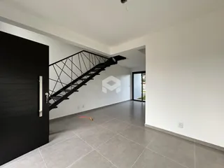 Hall de entrada com escada e piso cinza claro em uma propriedade.