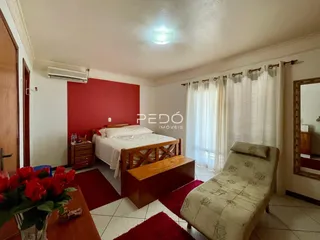 Quarto com cama de madeira e decoração vermelha em um imóvel no Brasil.