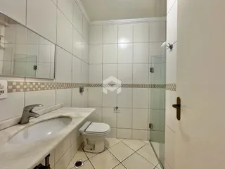 Banheiro com revestimento de azulejos brancos e piso claro.