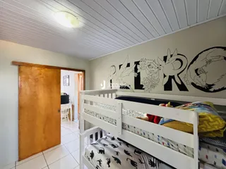 Quarto com cama de madeira e decoração de parede em Lajeado.