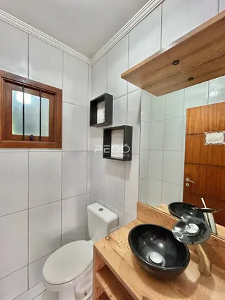 Foto de um banheiro com azulejos brancos e bancada de madeira.