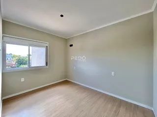 Sala de estar com piso de madeira clara e grande janela.