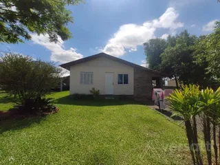 Fachada de uma casa em Lajeado, Brasil, com gramado verde e árvores ao fundo.
