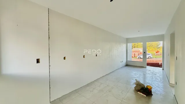 Interior de um espaço amplo com paredes brancas e piso de cerâmica.
