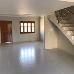 Ambiente interno de uma sala com piso claro e parede branca.
