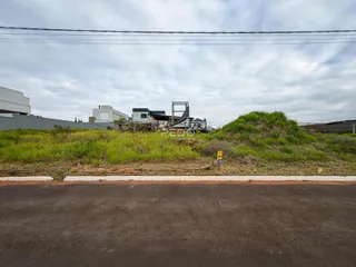 Vista da propriedade com vegetação e estruturas ao fundo.