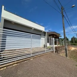 Foto da fachada de uma residência com portão de garagem e grade metálica.