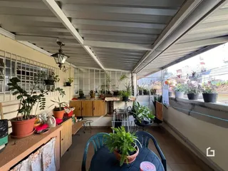 Vista de uma varanda coberta com plantas e móveis de madeira.