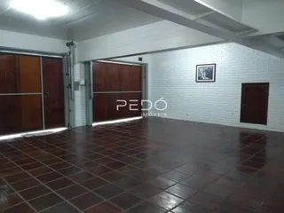 Interior de um ambiente com piso de ladrilhos marrons e portas de madeira.
