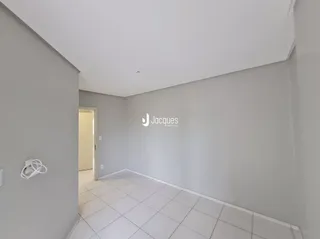 Corredor com piso de cerâmica e paredes brancas.