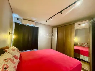 Quarto com cama vermelha e cortinas escuras.