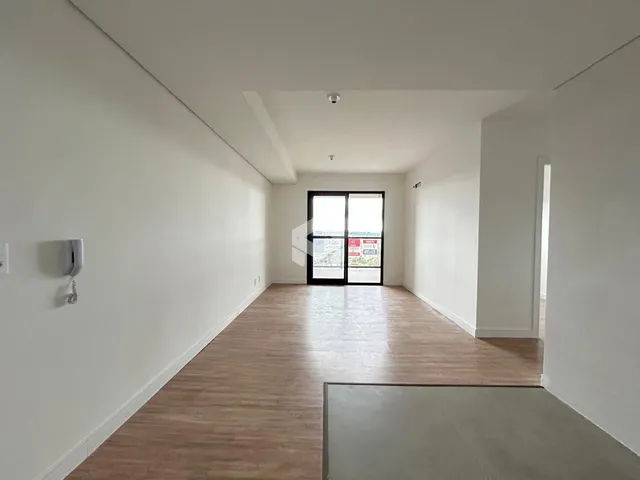 Interior de um corredor com piso de madeira clara e paredes brancas.
