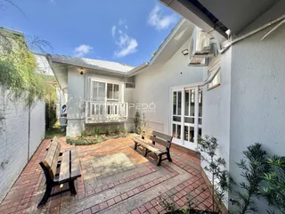 Fachada de uma residência em Lajeado, Brasil, mostrando um pátio externo com bancos de madeira.
