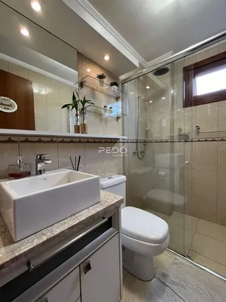Foto de um banheiro com revestimento cerâmico e box de vidro.