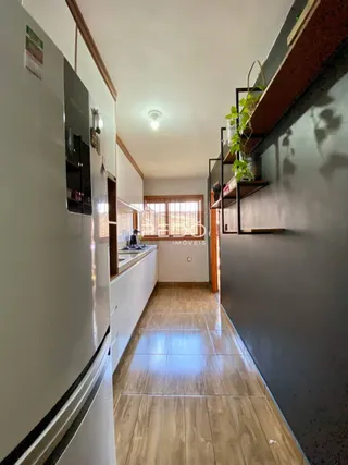 Vista de um corredor com armários brancos e piso de madeira em uma propriedade.