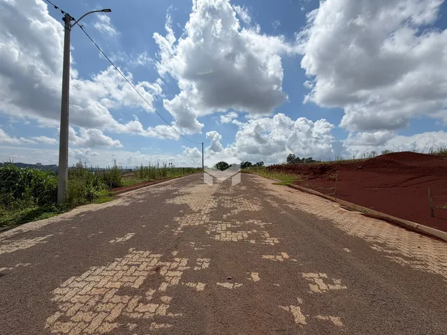 Uma estrada pavimentada se estende por uma paisagem de terra vermelha sob um céu nublado.