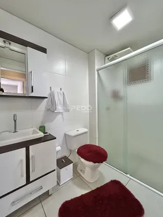 Banheiro com box de vidro e revestimento branco.