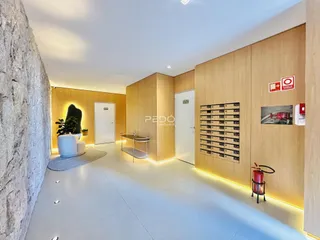 Hall de um apartamento moderno com revestimento de madeira e piso claro.