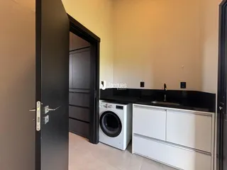 Vista da cozinha com bancada escura e eletrodomésticos brancos.