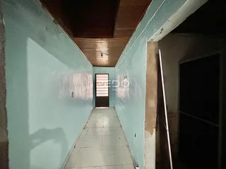 Corredor longo com paredes azuis claras e piso de cerâmica.
